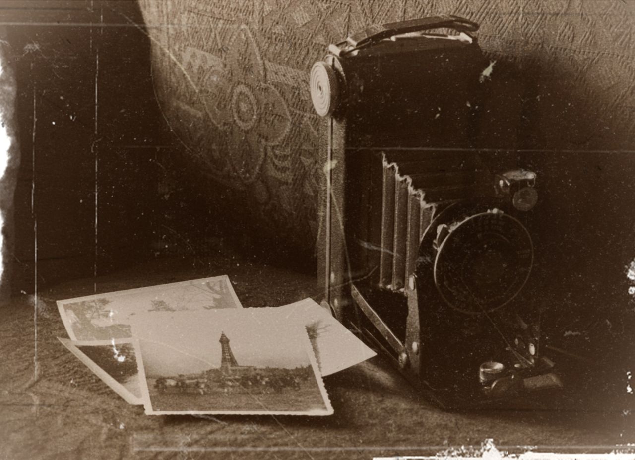 Sepia-toned image of a vintage camera with old photographs, capturing nostalgic memories.